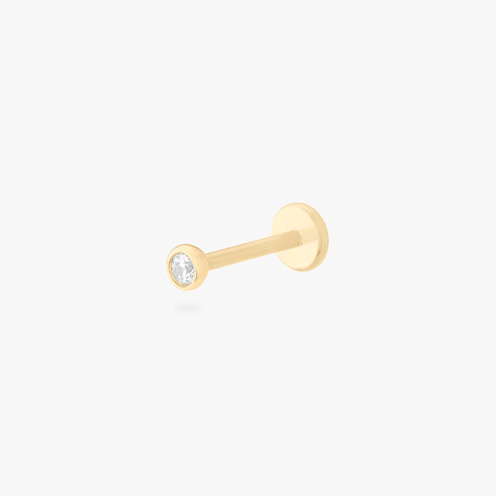 This is an image of a 14k gold flatback with a bezel setting and clear stone on ear.