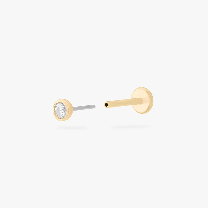 This is an image of a 14k gold flatback with a bezel setting and clear stone on ear. color:null|14k gold