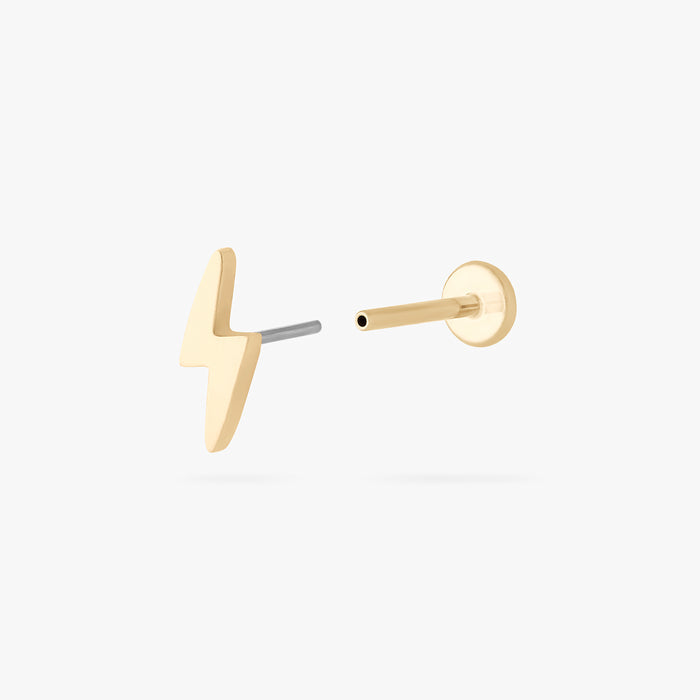 This is an image of a 14k gold flatback stud that is shaped like a lightning bolt separated from labret