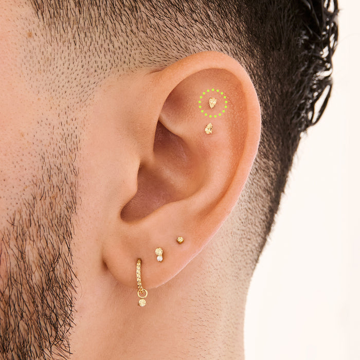 This is an image of a 14K gold flatback stud with a pear shaped topaz cz stone circled on an ear.