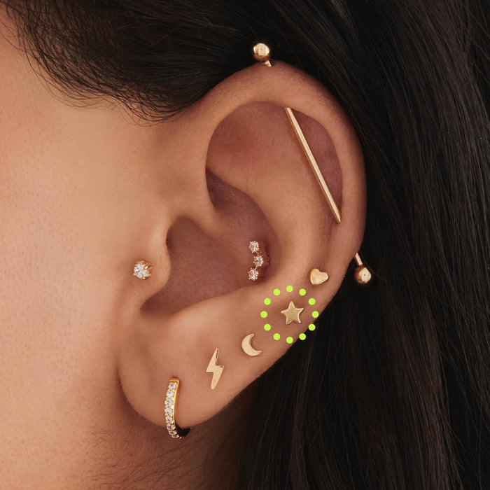 This is an image of a 14K gold flatback stud that is in the shape of a star on ear.