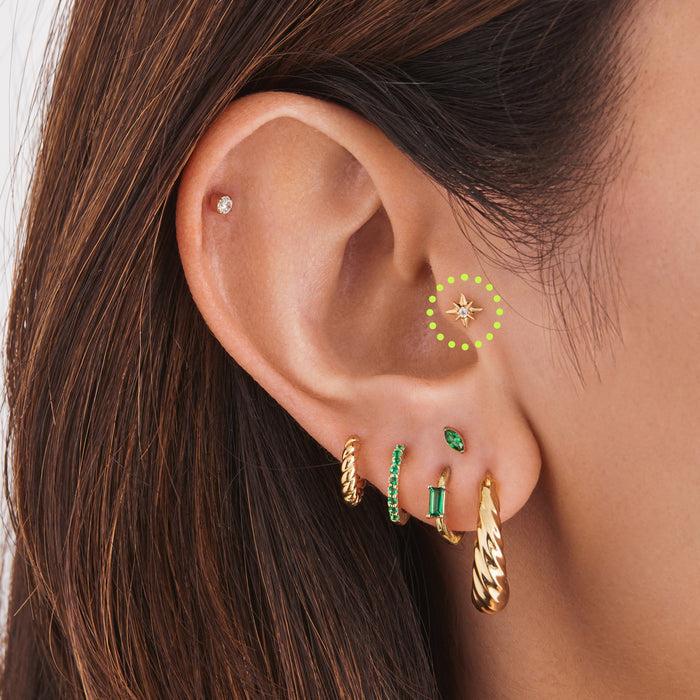 This is an image of a 14K gold flatback stud with a pointed star with a clear cz stone in the center on ear. [hover] color:null|gold|gold/clear