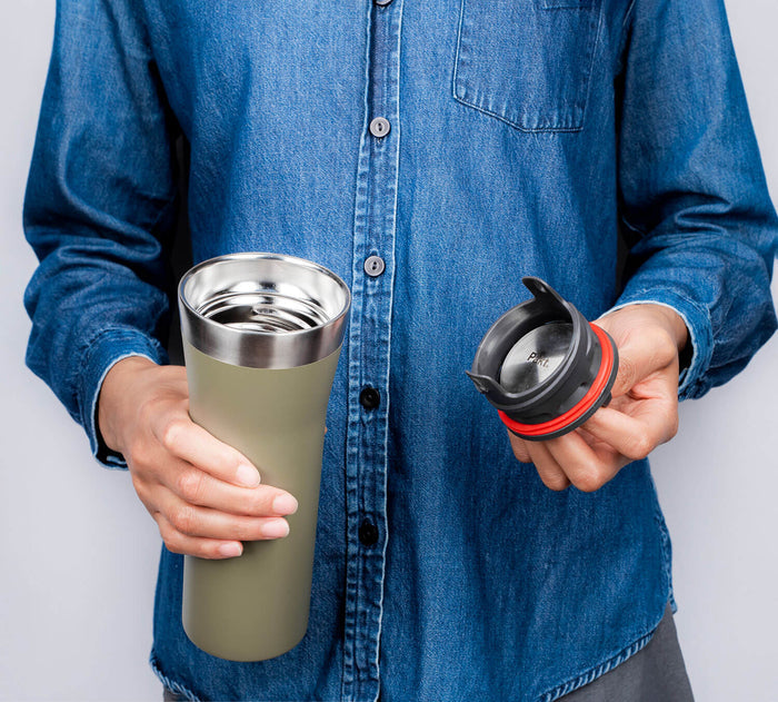 Front view of 16oz Leakproof Travel Mug in green held by a person, showing stainless interior and removed black lid with red silicone seal