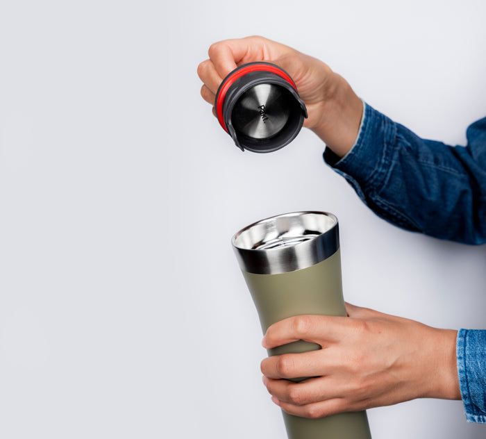 Close-up of 16oz Leakproof Travel Mug with lid removed showing stainless-steel interior and red silicone seal against a light gray background