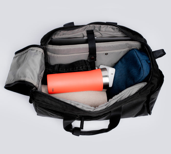 Top view of orange 16oz Leakproof Travel Mug with stainless rim inside open black duffel bag with laptop sleeve