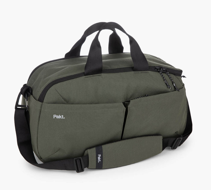 Olive-green Pakt. duffel bag with black handles and shoulder strap and front pockets visible