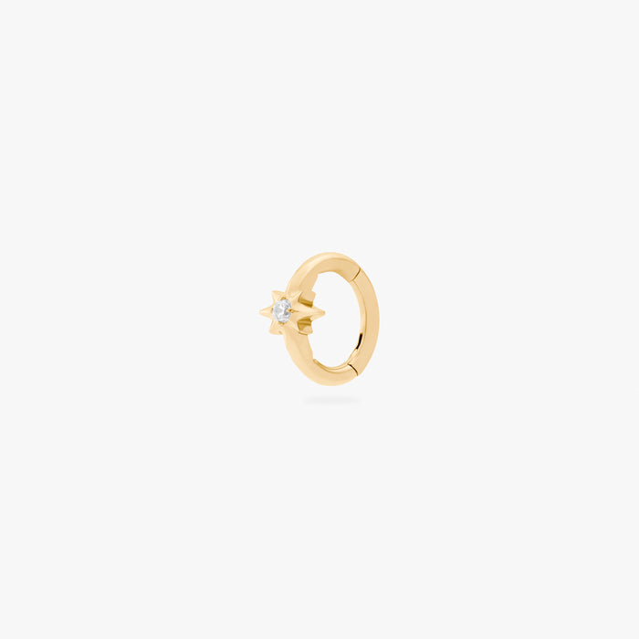 This is an image of a gold-toned titanium clicker with a twinkle-star shape that features a crystal CZ in the center. This clicker is 6mm in diameter.