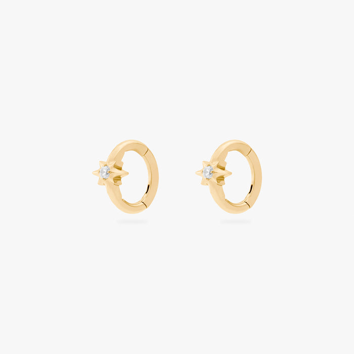 This is an image of a pair of gold-toned titanium clickers with twinkle-star shapes that feature crystal CZs in the center. These clickers are 6mm in diameter.