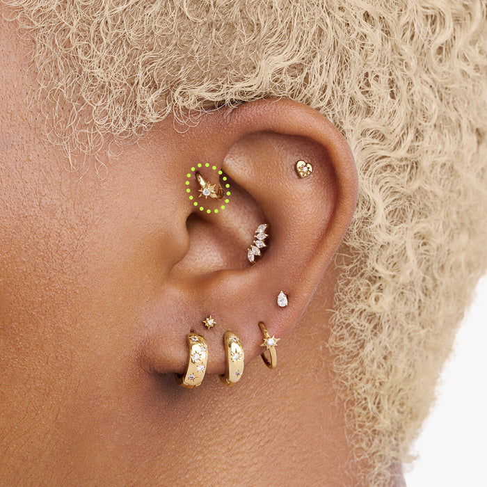 This is an image of a gold-toned titanium clicker with a twinkle-star shape that features a crystal CZ in the center circled on an ear. This clicker is 6mm in diameter.