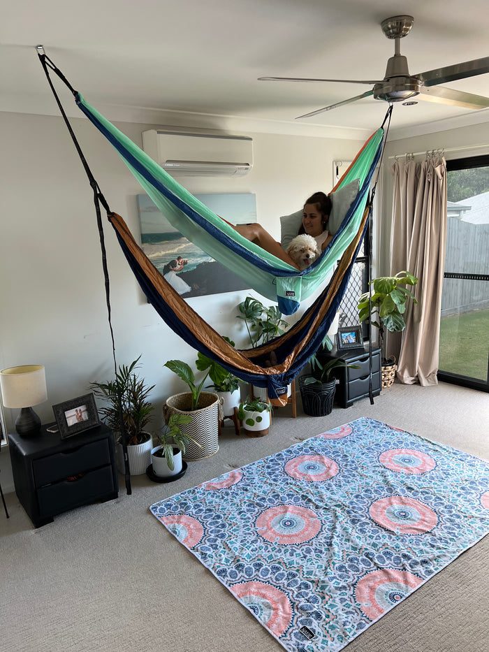 Hammock anchor point securing green and navy striped hammock to ceiling in indoor room