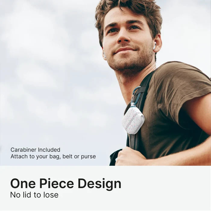 A smiling man with light brown hair, in a brown t-shirt and wireless earbuds, has a Catalyst Case US AirPods Pro (Gen 3/2/1) Waterproof Case + Carabiner clipped to his backpack. Text: "Carabiner Included. One-piece design—attach anywhere.