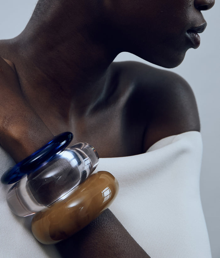 Close-up of model in white top with Arc Cuffs in Mocha and Lilac and Ridge Cuff in Electric.