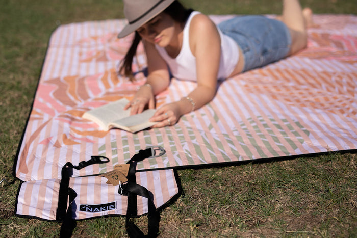 Woman enjoying a book at a Nakie picnic, surrounded by nature and relaxation