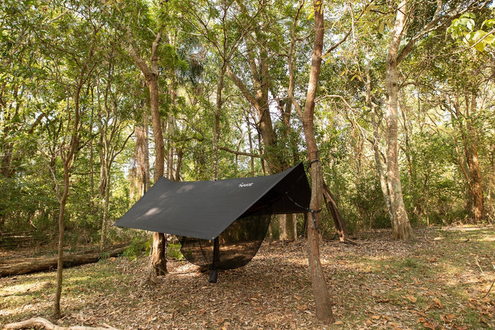 A Nakie hammock ultralight no knot tarp fully set up at a campsite