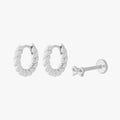 This image shows a set of silver earrings.  The set includes a pair of silver french twist huggies and a singular bow flatback stud.