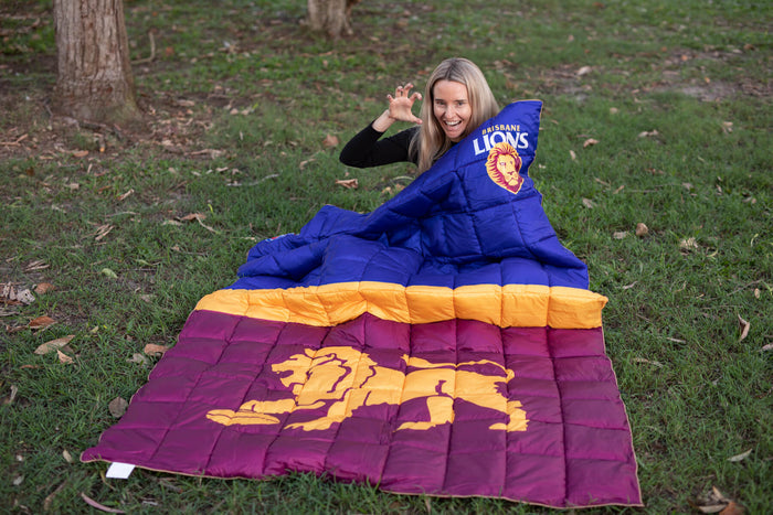 Brisbane Lions puffy blanket in blue, gold, and maroon with team logo, displayed outdoors on grass