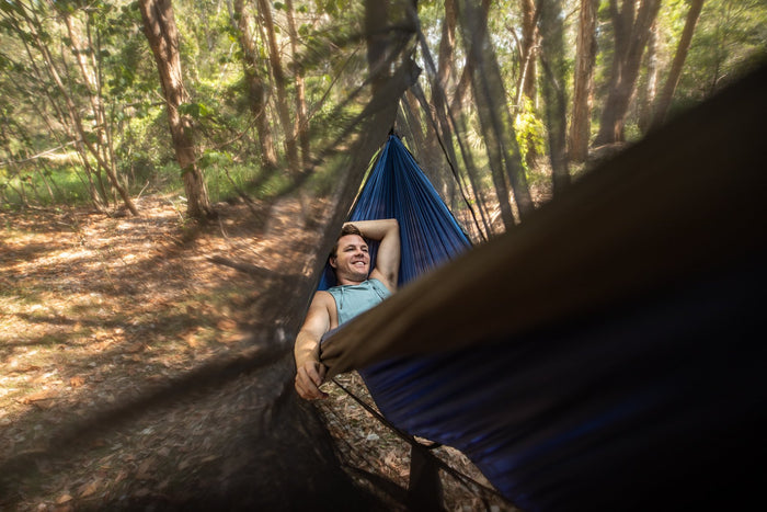 A smiling man lying comfortably in a Nakie hammock