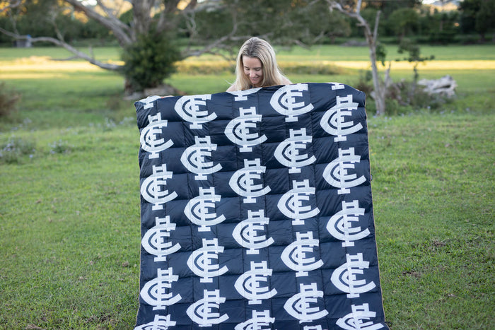 Navy quilted blanket with white Carlton Blues AFL logo pattern, displayed outdoors