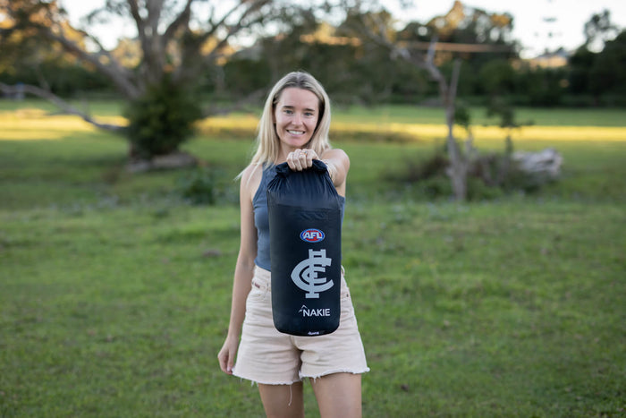 Black Carlton Blues AFL puffy blanket with white logo and Nakie branding, displayed outdoors
