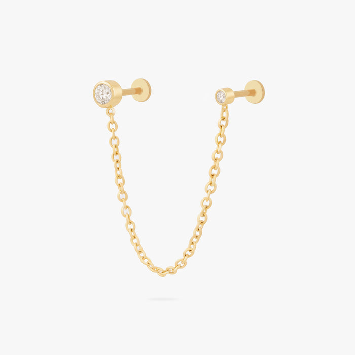 this image shows a titanium gold chain connector earring featuring a circular CZ flatback stud and a circular clear cz stud flatback linked by a delicate gold chain