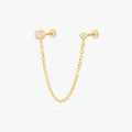 this image shows a titanium gold chain connector earring featuring a circular CZ flatback stud and a circular clear cz stud flatback linked by a delicate gold chain