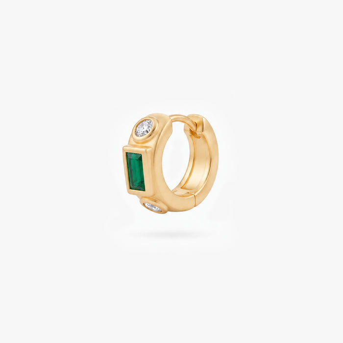 This image shows the front view of a 14k gold plated huggie with three cz stones. One green square in the middle and two clear circular stones on the outside.