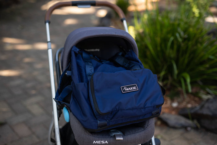 Navy recycled tote bag with Nakie branding, attached to stroller seat in front-facing view