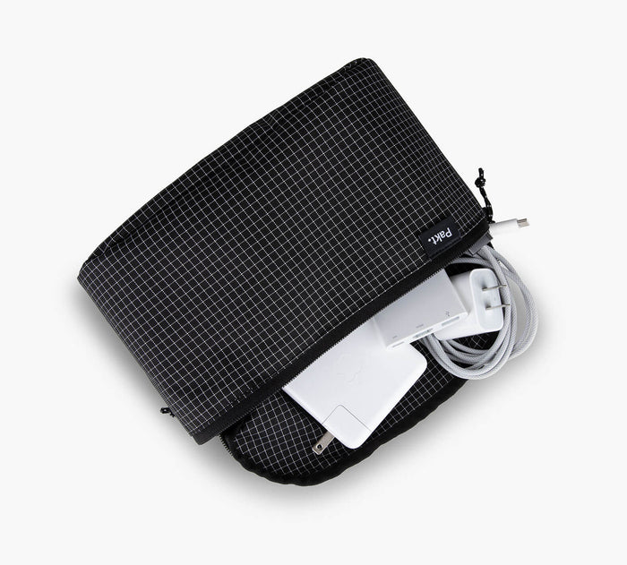 Top-down view of black grid Clip-in pouch unzipped showing white power adapter and braided cable on white background