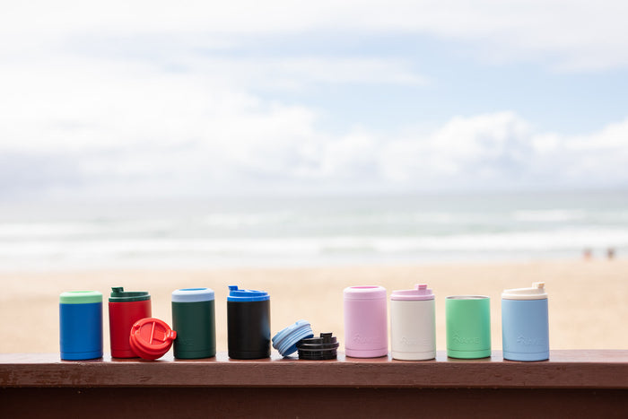 Collection of insulated drink containers in various colors including blue, red, green, black, pink, white, and mint green