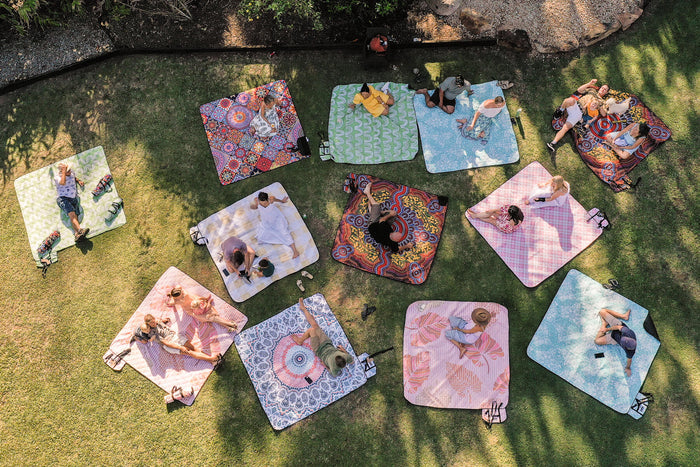 Image of people sitting or lying on Nakie's recycled picnic blankets in different colors