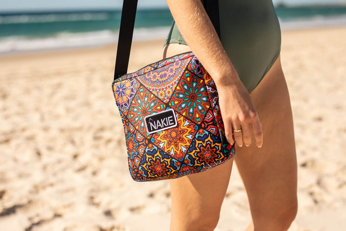 Recycled XL sand-free beach blanket with multicolored geometric mandala pattern, worn as shoulder bag on beach