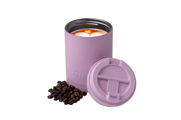 Dusty pink insulated coffee tumbler with black lid, filled with latte art, shown with matching lid and coffee beans.