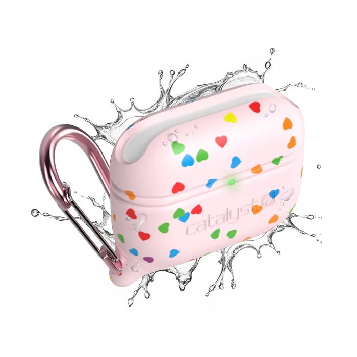 A Catalyst Case US AirPods Pro (Gen 3/2/1) Waterproof Case with a pink rainbow heart design and metallic pink carabiner is shown with splashing water, highlighting its rugged, water-resistant build against a white background.