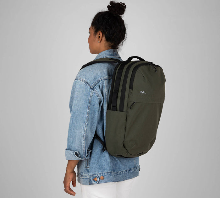 Rear three-quarter view of Everyday 22L Backpack in Forest on a model showcasing dual zippered compartments, side water bottle pocket, and padded straps
