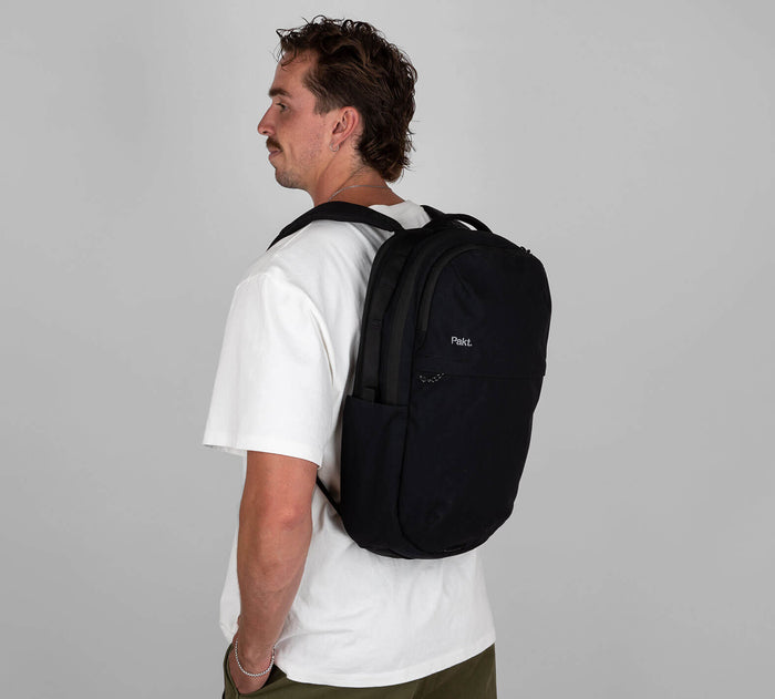 Side view of Everyday 22L Backpack in Black worn by model showing padded straps and side water pocket on grey background