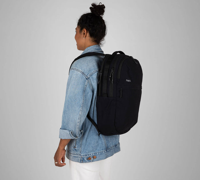 Back-left view of Everyday 22L Backpack in Black on model, showing dual compartments and side water pocket