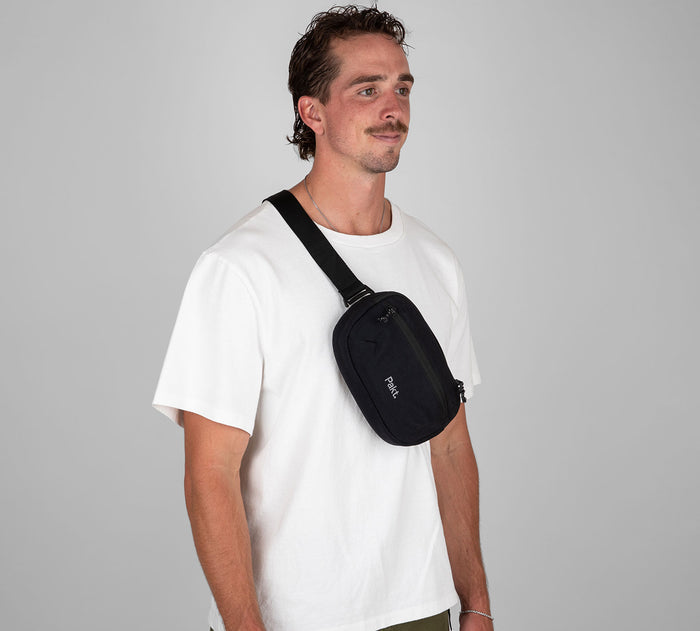 Black Pakt. 3L sling bag worn crossbody on a male model's chest, white T-shirt