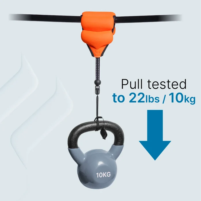 An orange Floating Wrist Lanyard by Catalyst Case US with a black clip holds a gray 10kg kettlebell from a black cord. Text reads "Pull tested to 22lbs / 10kg" with a blue downward arrow, showing the lanyard and clip's strength capacity.