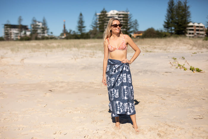 Geelong Cats navy beach towel with white logo print, worn as wrap on sandy beach