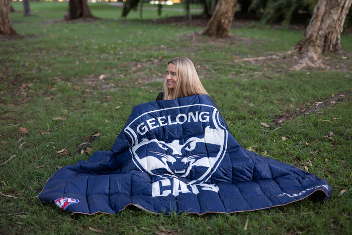 Navy Geelong Cats AFL puffy blanket with white team logo and text, displayed on grass outdoors.