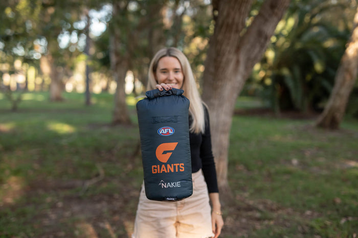 GWS Giants navy dry bag with orange logo and Nakie branding, held by person outdoors