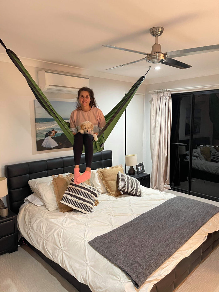 Green and black hammock with anchor points, suspended in bedroom between ceiling mount and bed frame