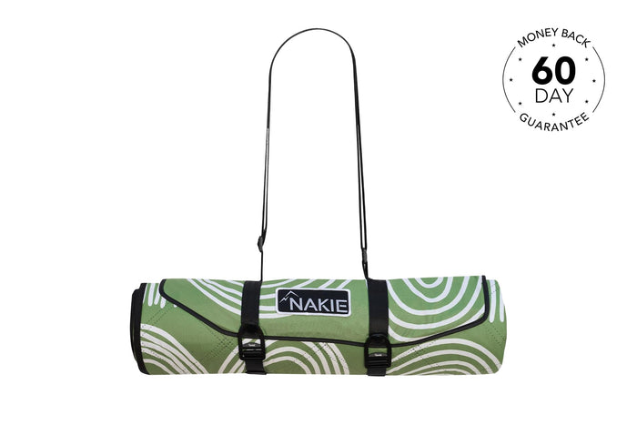 Green and white swirl patterned picnic blanket rolled with black carrying straps and Nakie logo label