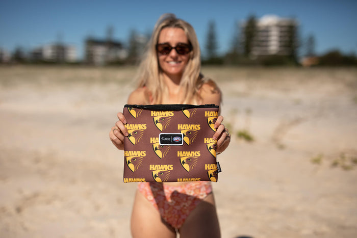 Brown Hawks AFL recycled sand-free beach towel with repeating hawk head logo and yellow text, displayed on beach