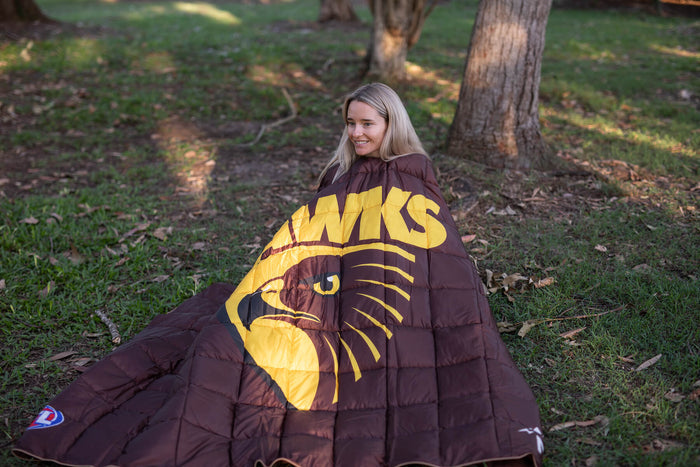 Hawthorn Hawks brown and yellow puffy blanket with eagle logo, draped around person outdoors