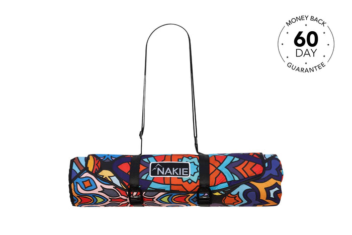 Colorful abstract patterned recycled picnic blanket rolled with black straps and Nakie logo patch