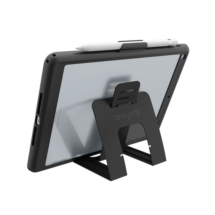 A black tablet stand holds an iPad (Gen 6/5) 9.7" in landscape, secured by a Catalyst Case US Impact Protection Case. A white stylus sits on top, with the plain white background emphasizing the caseÃƒÂ¢Ã¢â€šÂ¬Ã¢â€žÂ¢s protective design and style.