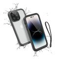 The Catalyst Case US iPhone 14 Pro Max Waterproof Case offers total protection, shown enclosing the phone with water splashes, a clear back revealing the Apple logo and triple camera, plus a black wrist strap attached.