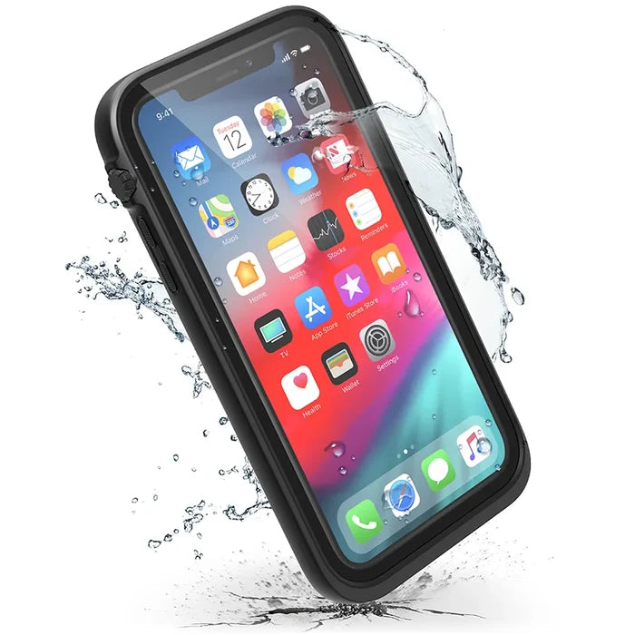 An iPhone XR in a Catalyst Case US waterproof case (Stealth Black) is shown with water splashes, highlighting its protective and water-resistant design. The vibrant screen displays common app icons on a colorful background.