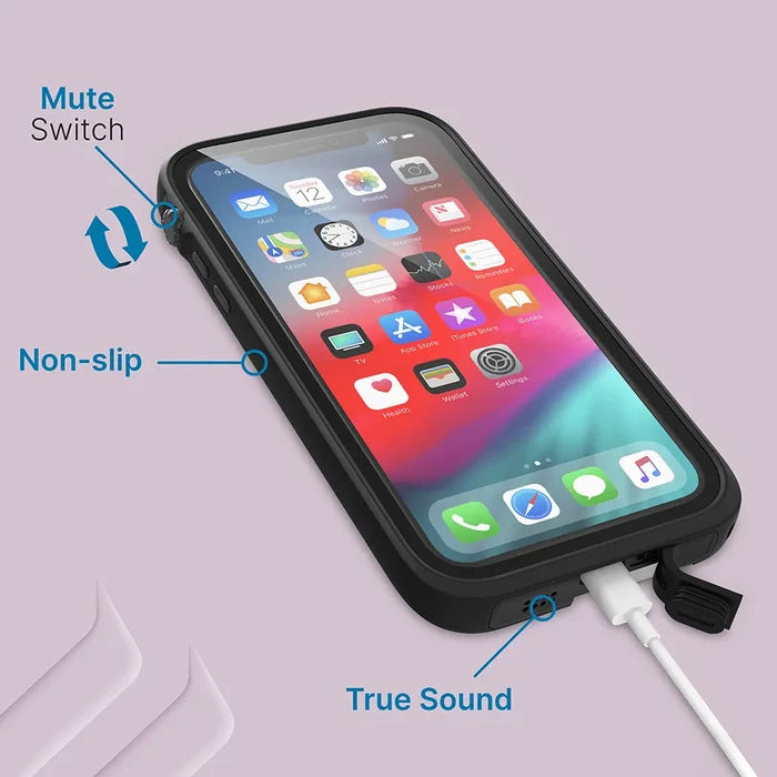 An iPhone XR in a Catalyst Case US waterproof case lies flat, screen on and charging with a white cable. Blue tags highlight “Mute Switch” by the side button, “Non-slip” grip, and “True Sound” at the covered charging port.